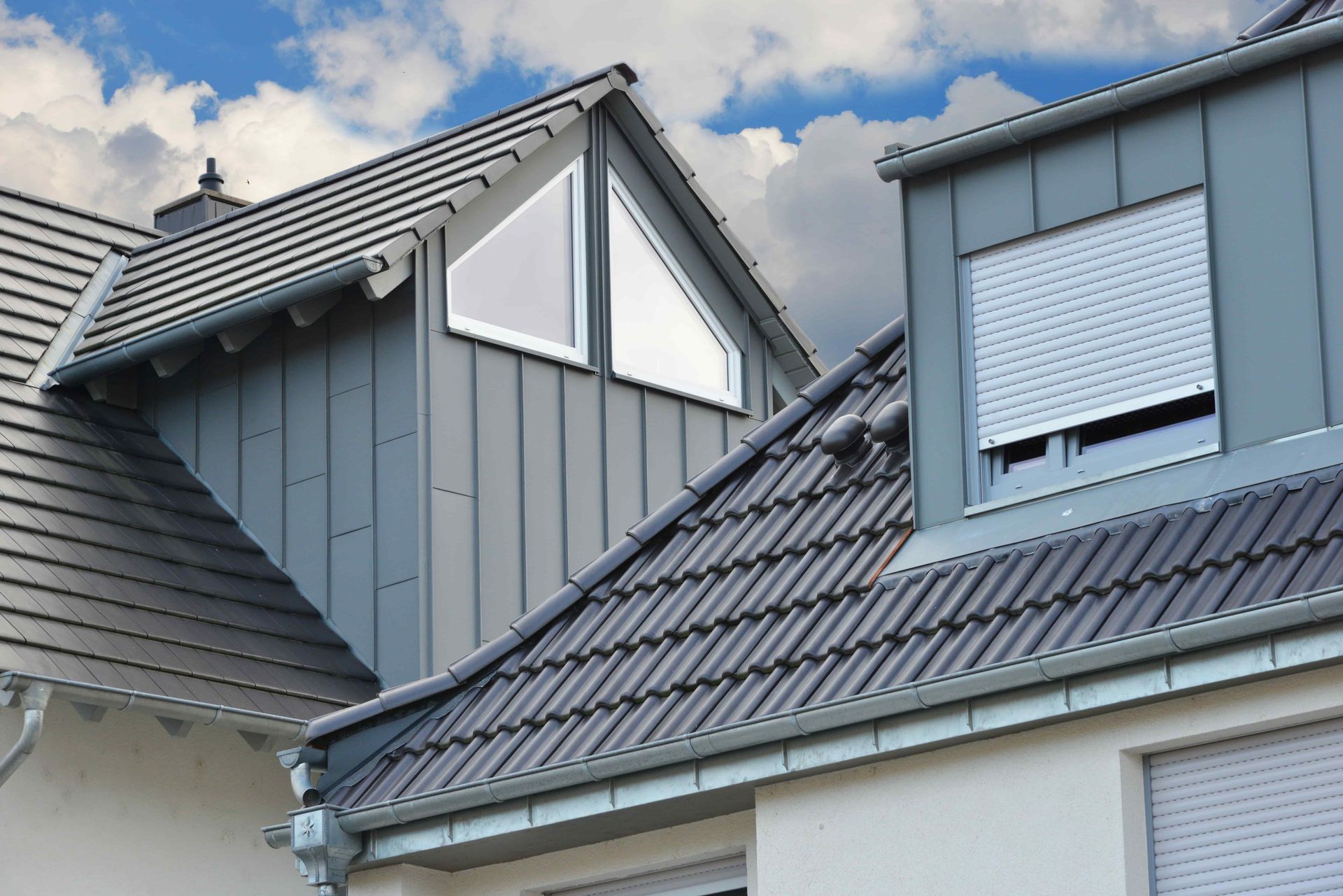 The roof of a house with a window and shutters on it.