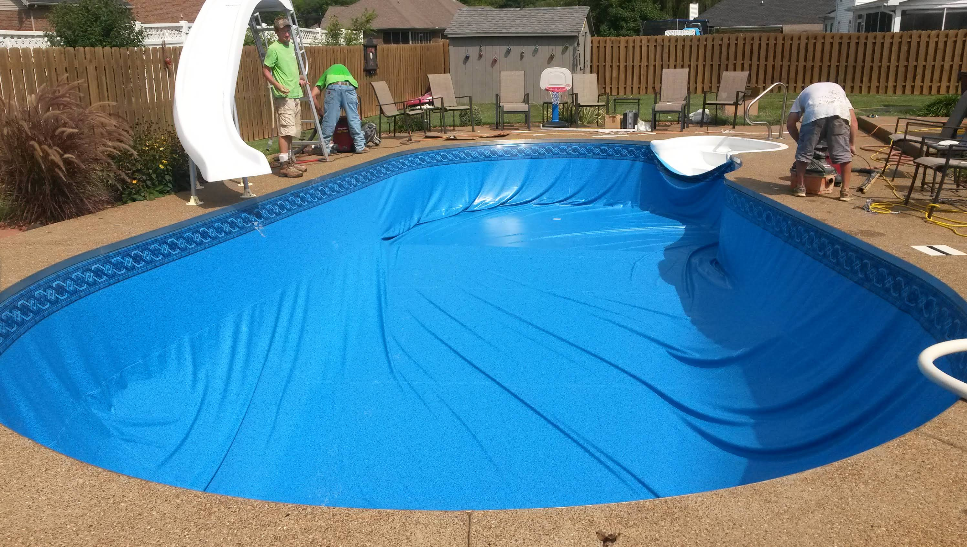 A blue swimming pool with a slide in the background