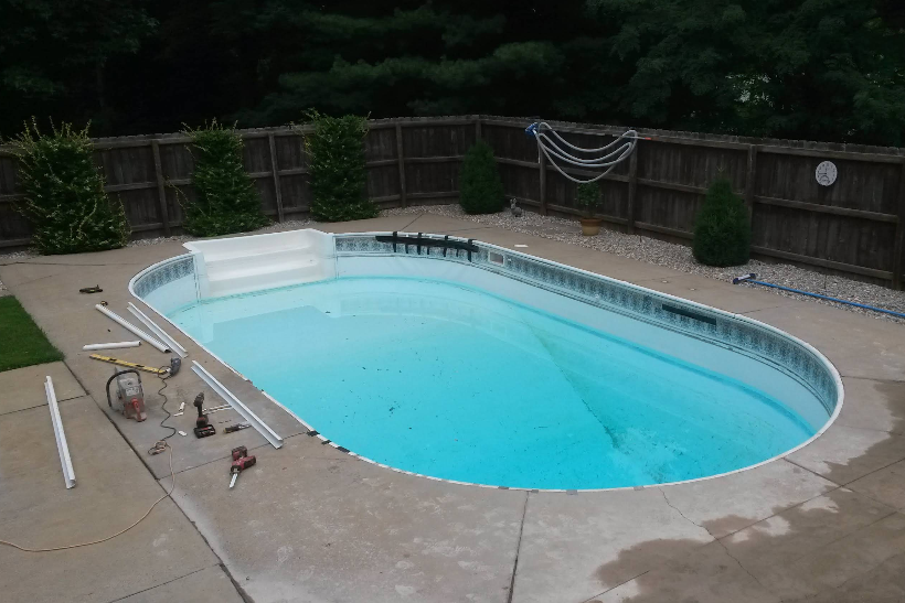 A large swimming pool is being remodeled in a backyard.