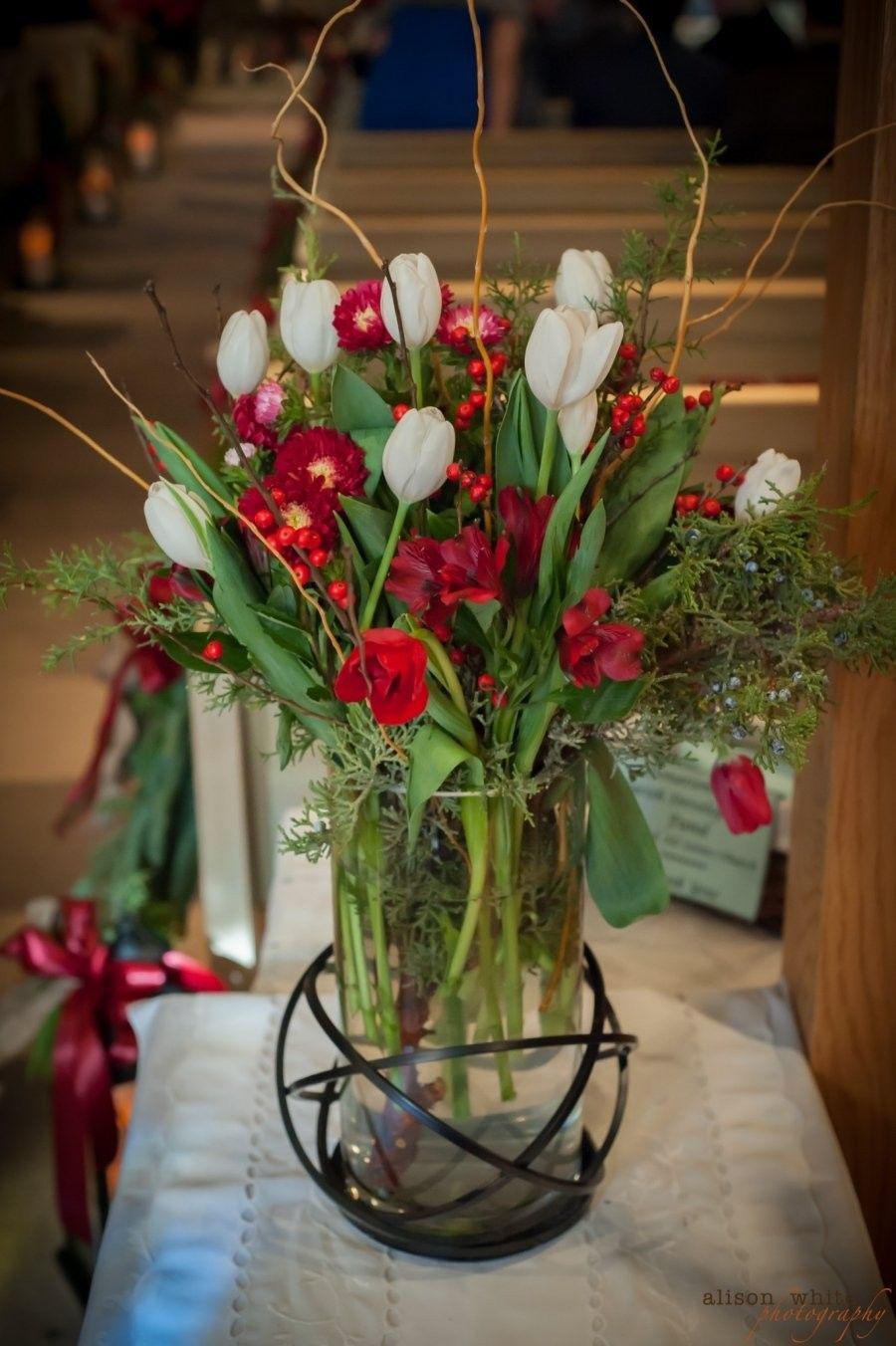 Red and white flower bouquet in a glass vase on a table