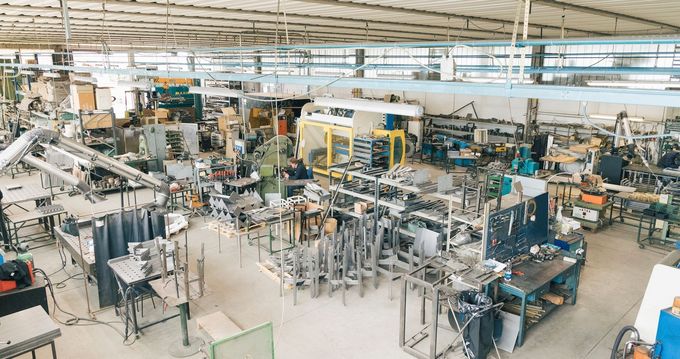 Un'officina industriale piena di macchinari per la lavorazione dei metalli, postazioni di lavoro e attrezzature sotto soffitti alti e inclinati.