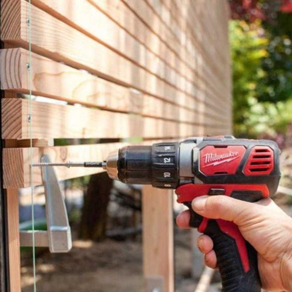A person is holding a milwaukee drill in their hand