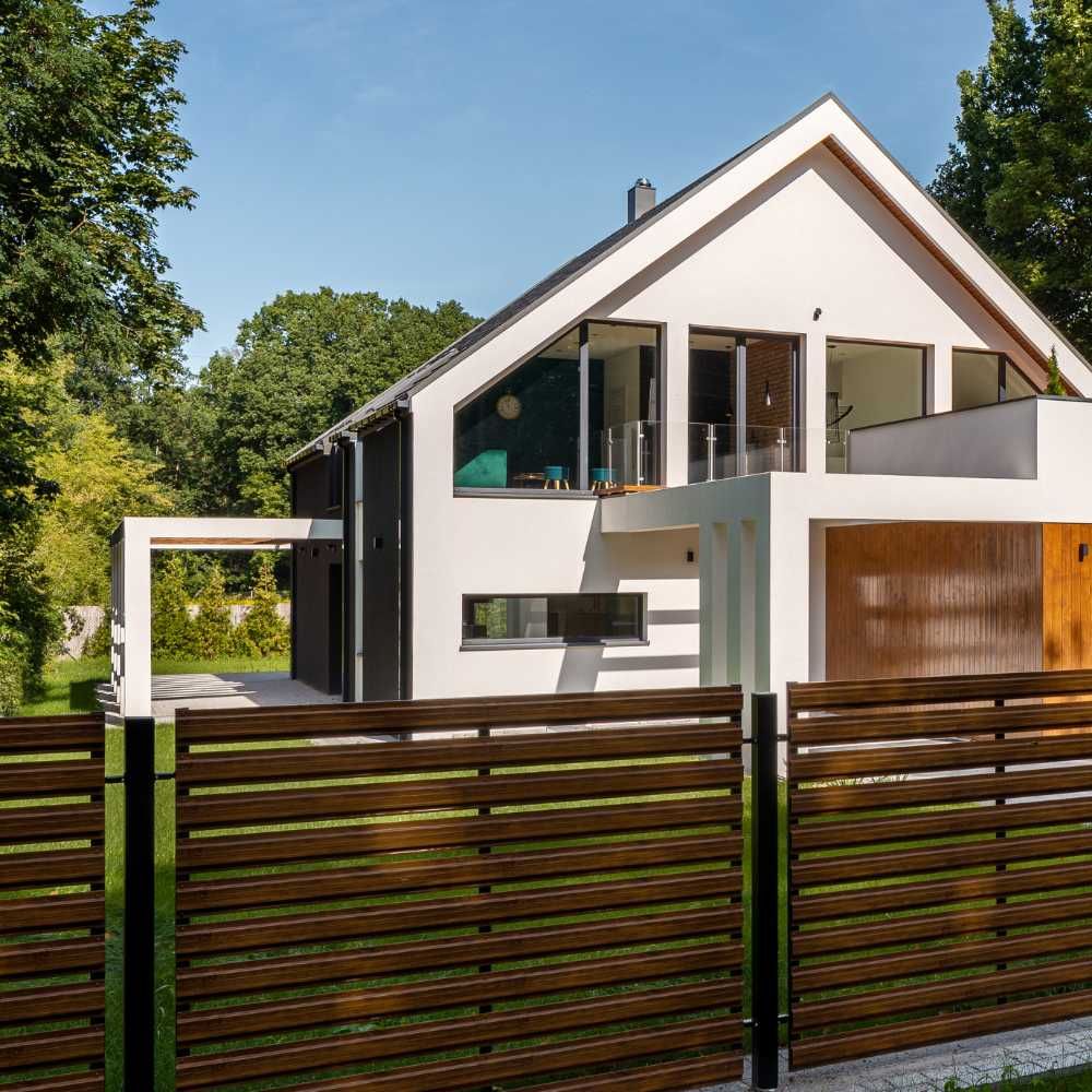 A modern house with a wooden fence in front of it.