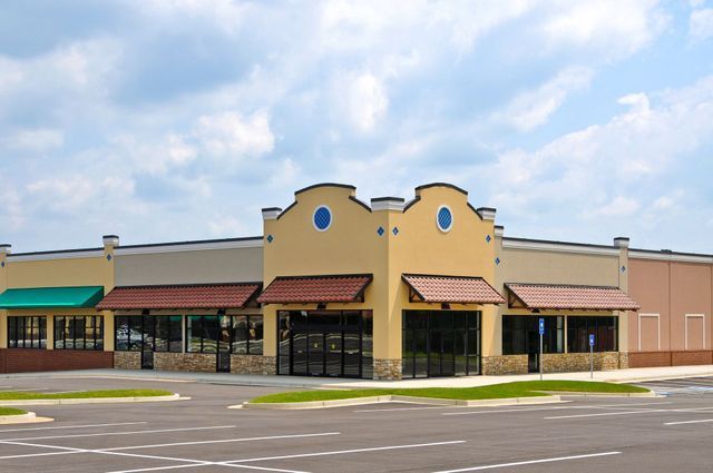 Commercial building with tan facade, brown awnings, and large glass windows; exterior shot.