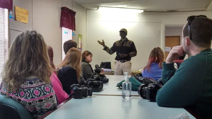Group of people smiling and talking outdoors, possibly volunteering.