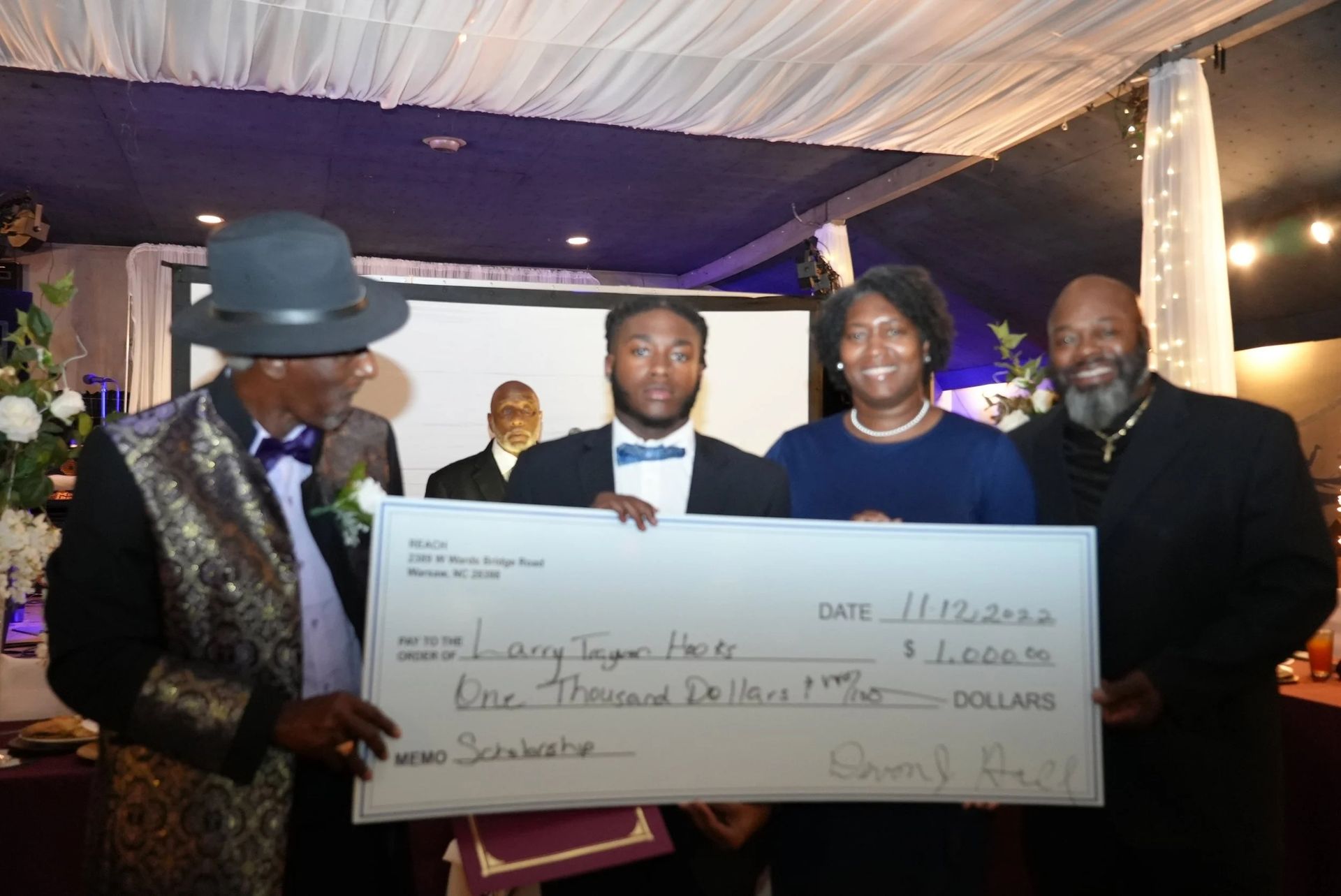 People holding a large check. Event setting, people smiling.