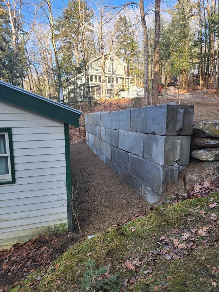 A concrete wall is being built next to a house in the woods.