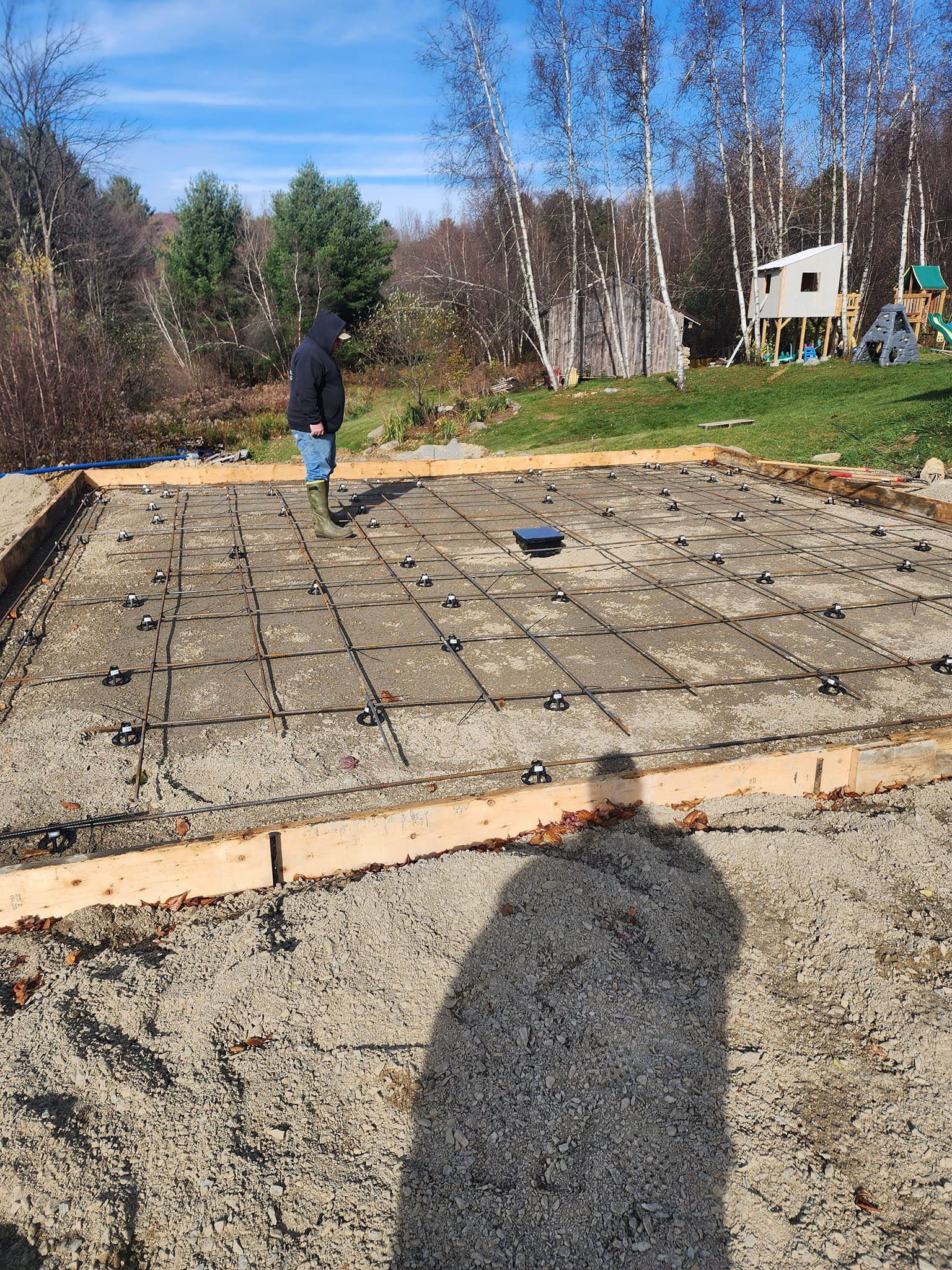 A man is standing on a concrete slab in a yard.