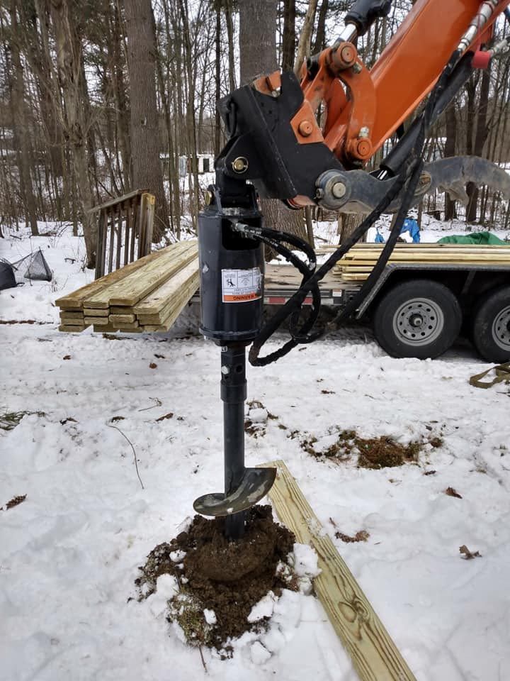 A machine is digging a hole in the ground in the snow.
