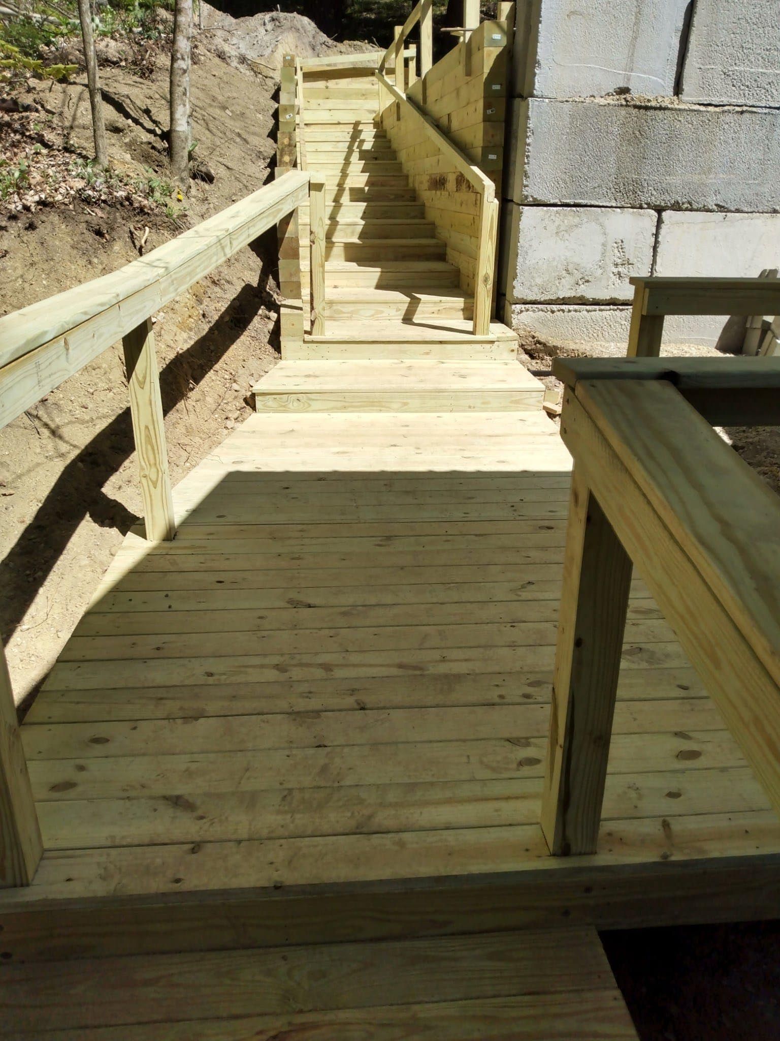 A wooden staircase with a railing going up a hill