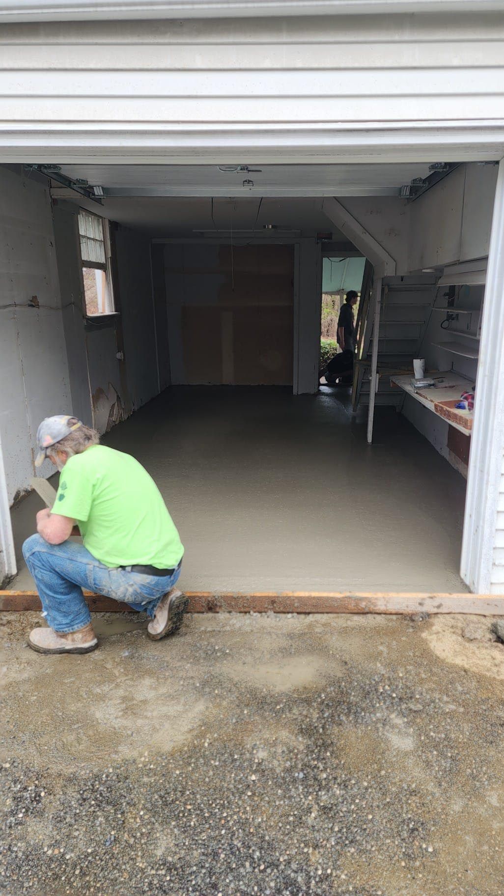 A man is kneeling down in front of a garage door.