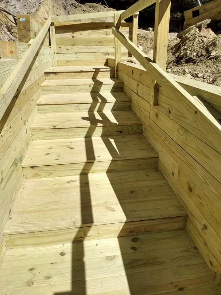 A wooden staircase with a railing and shadows on the steps.