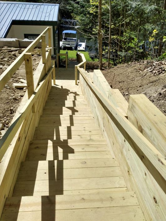 A wooden staircase with a railing leading up to a house