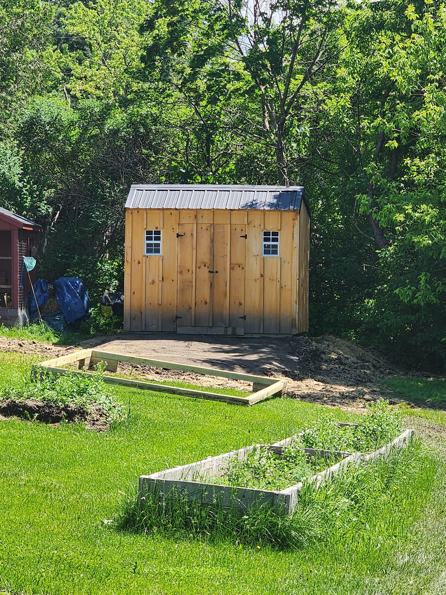 A small wooden shed is sitting in the middle of a lush green field.