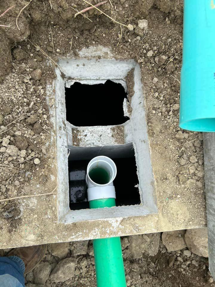 A green pipe is coming out of a hole in the ground.