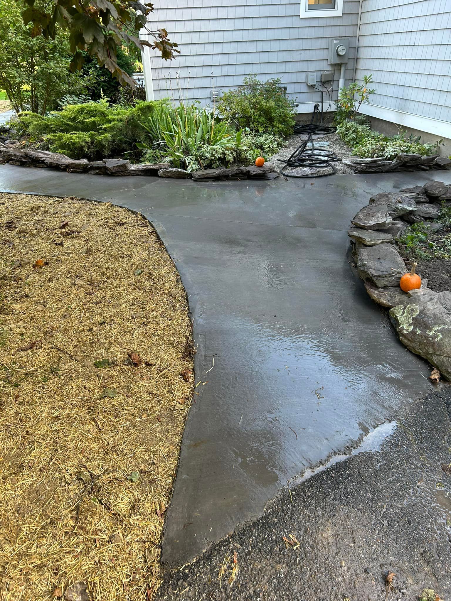 A concrete walkway leading to a house with pumpkins on it.