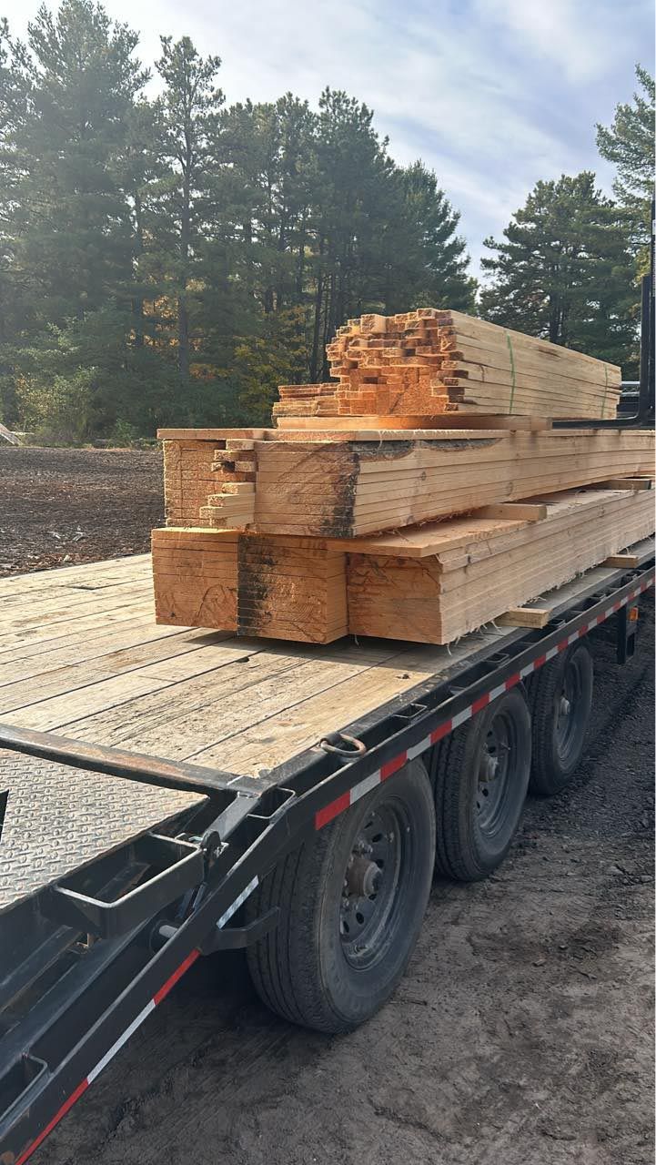 A trailer is loaded with a stack of wood.