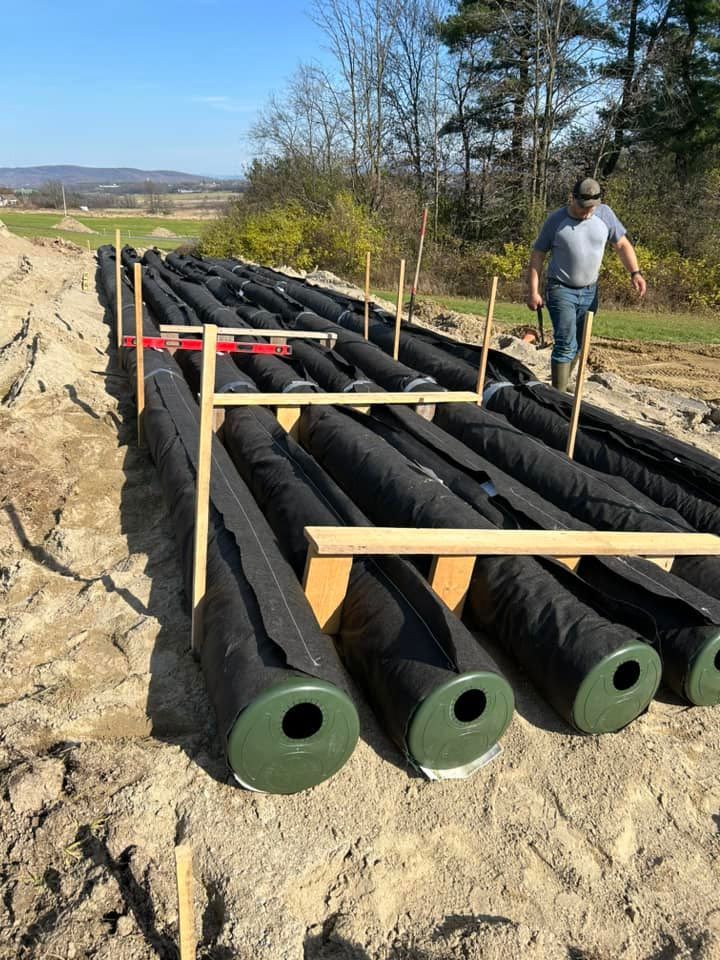 A man is standing next to a pile of rolls of fabric.