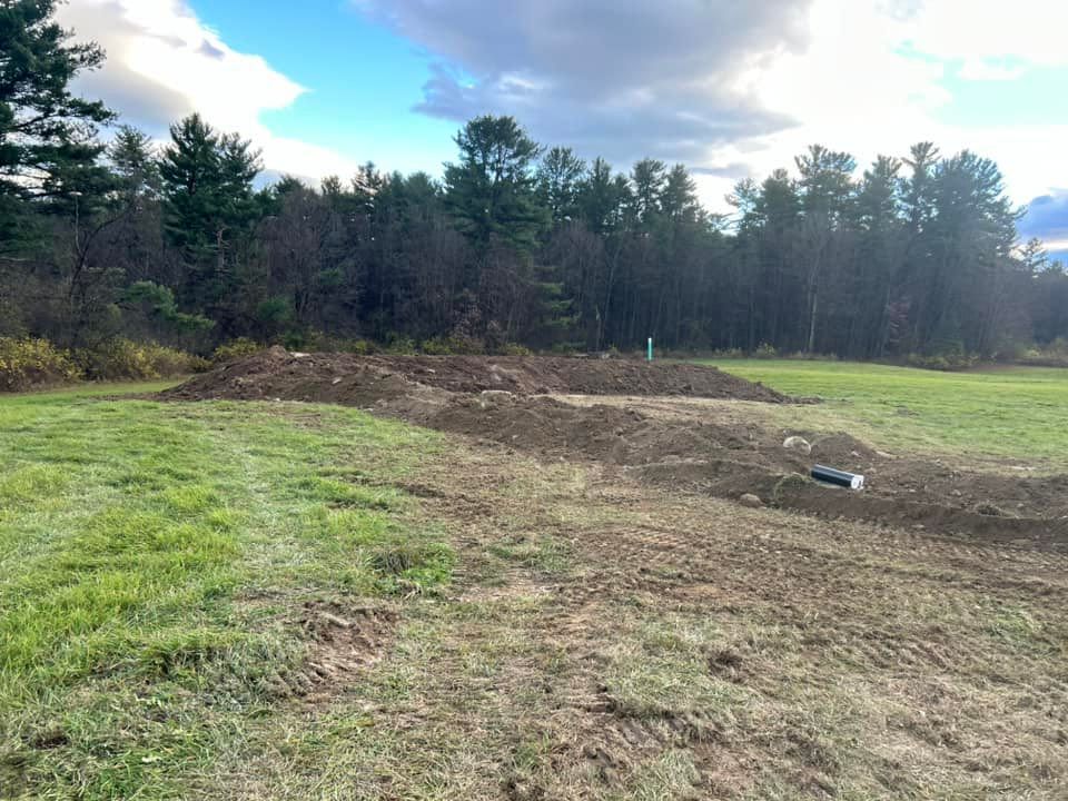 There is a large pile of dirt in the middle of a field.