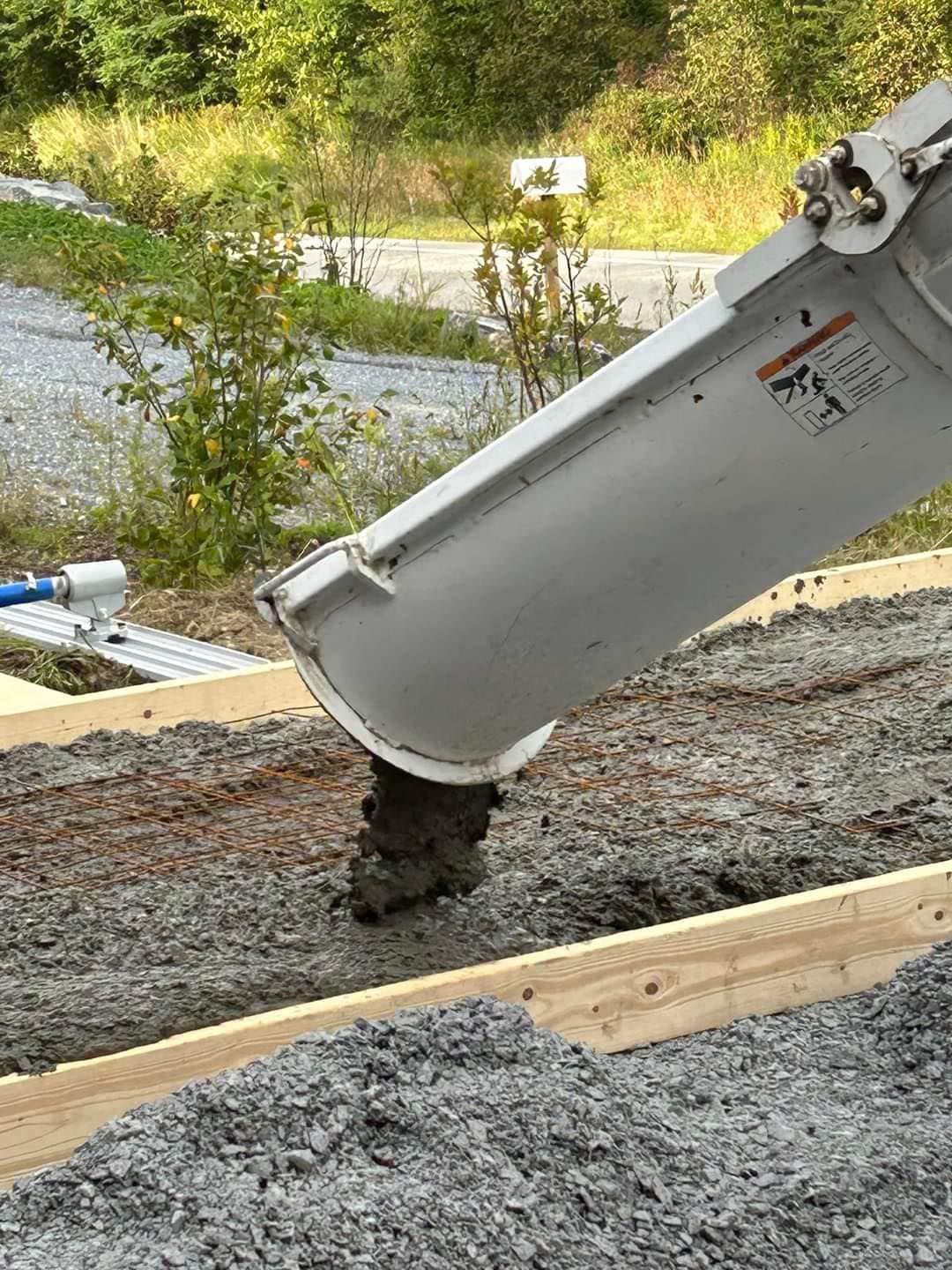 A concrete pump is pouring concrete into a wooden frame.