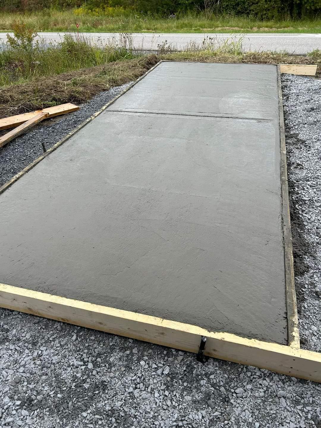 A large concrete slab is sitting on top of a gravel road.