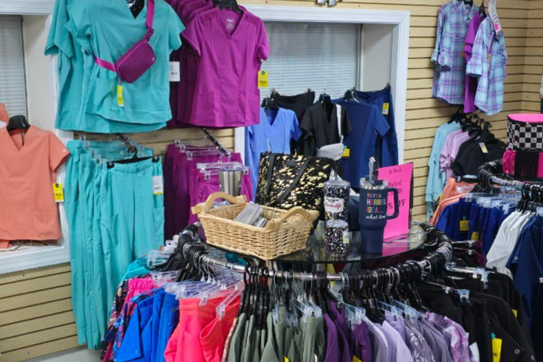 Clothing store display with scrubs in various colors, hanging on racks.