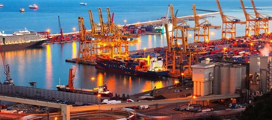 An aerial view of a harbor at night with lots of cranes and ships.