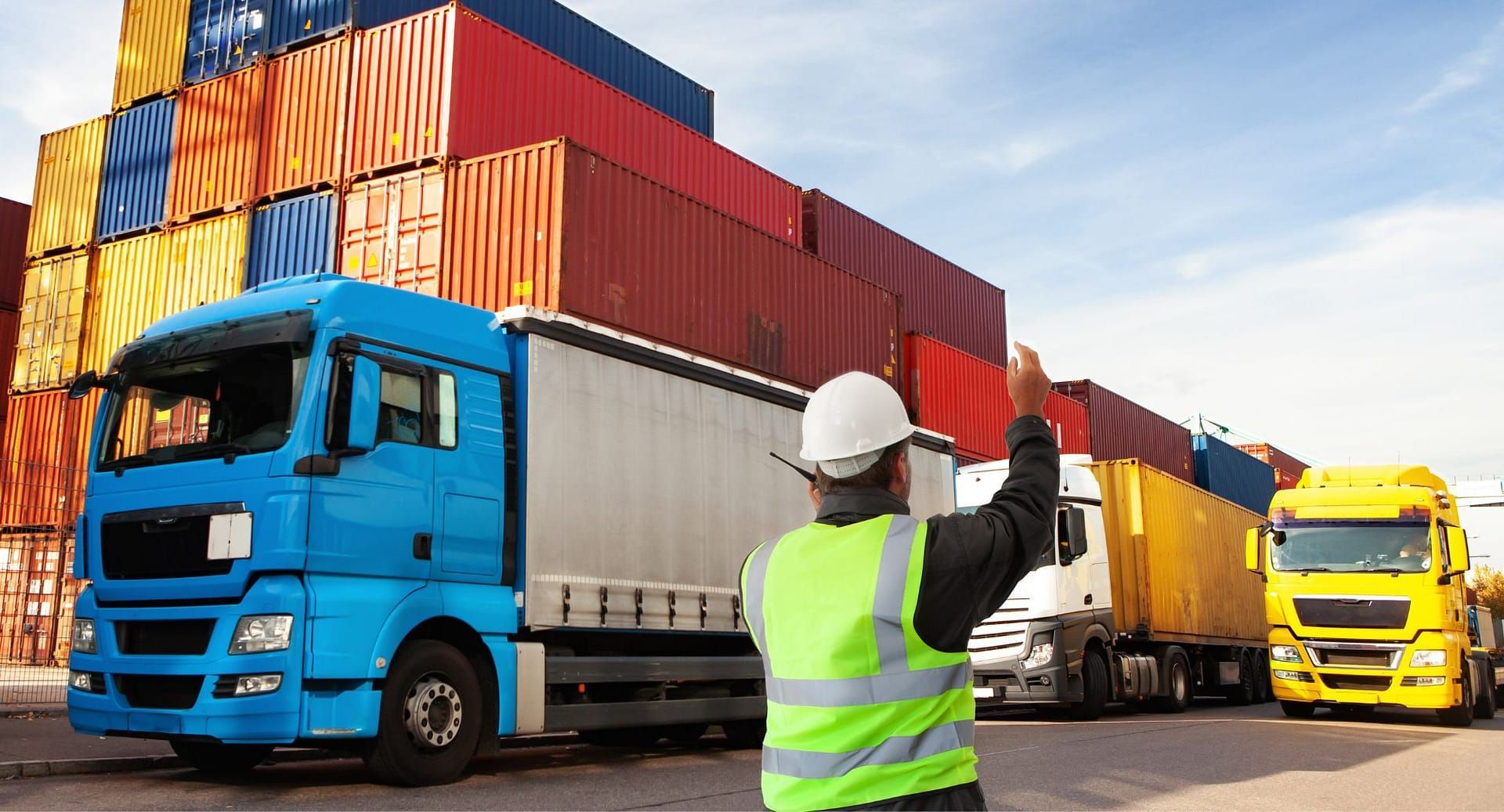 A man is standing in front of a row of trucks in a warehouse.