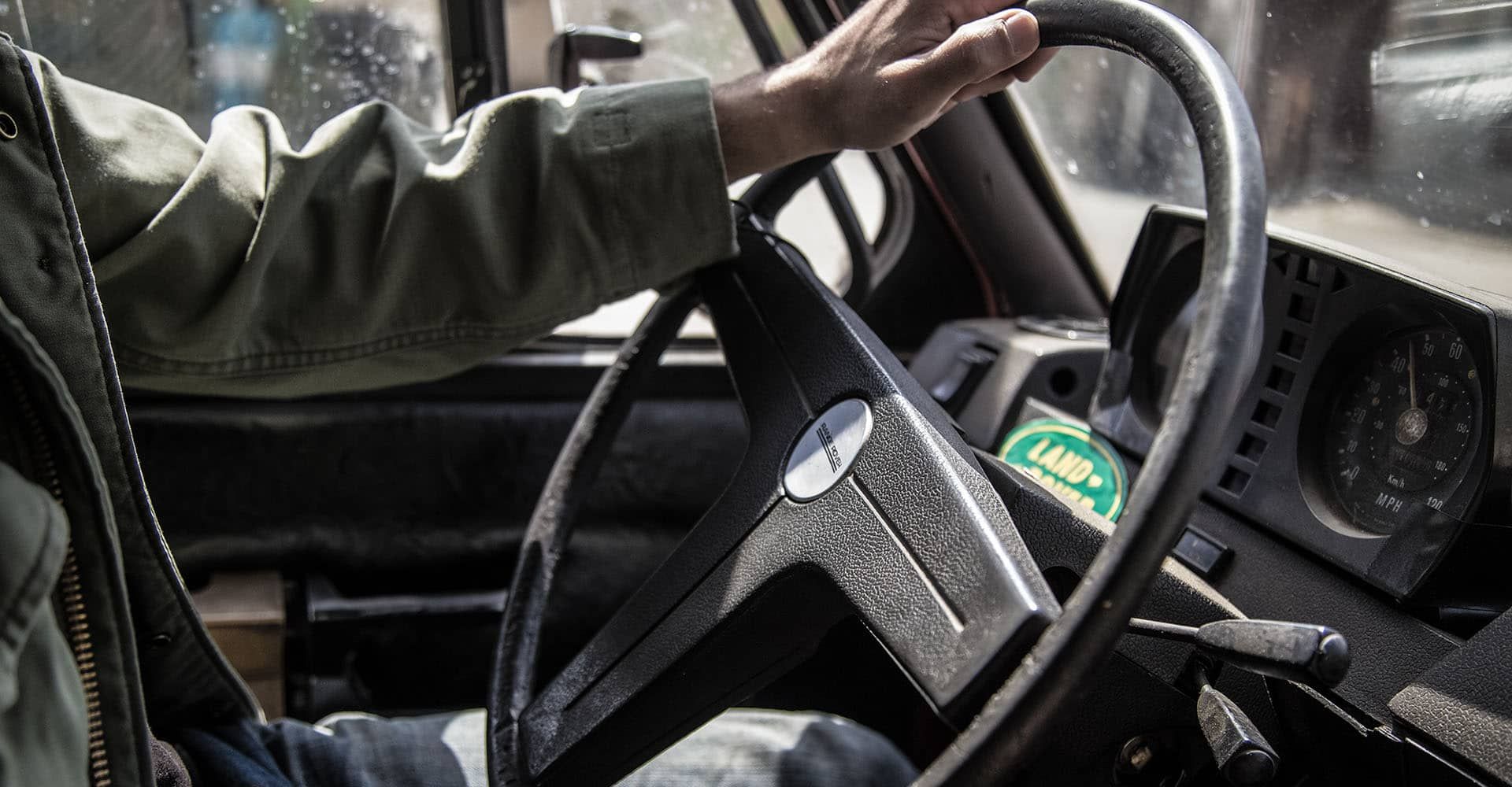 A man is driving a car and holding the steering wheel.