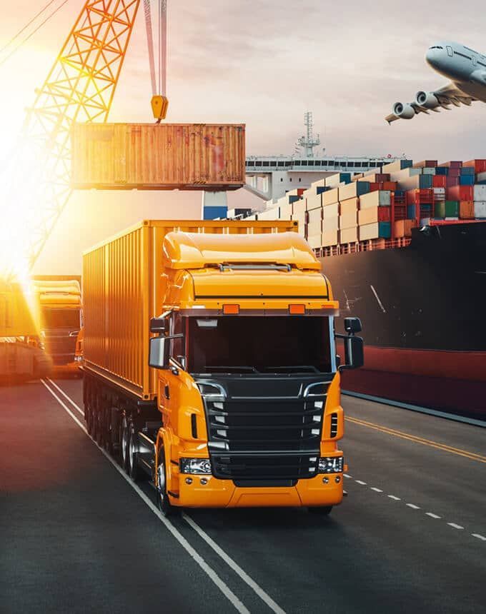 A truck is driving down a road next to a ship.