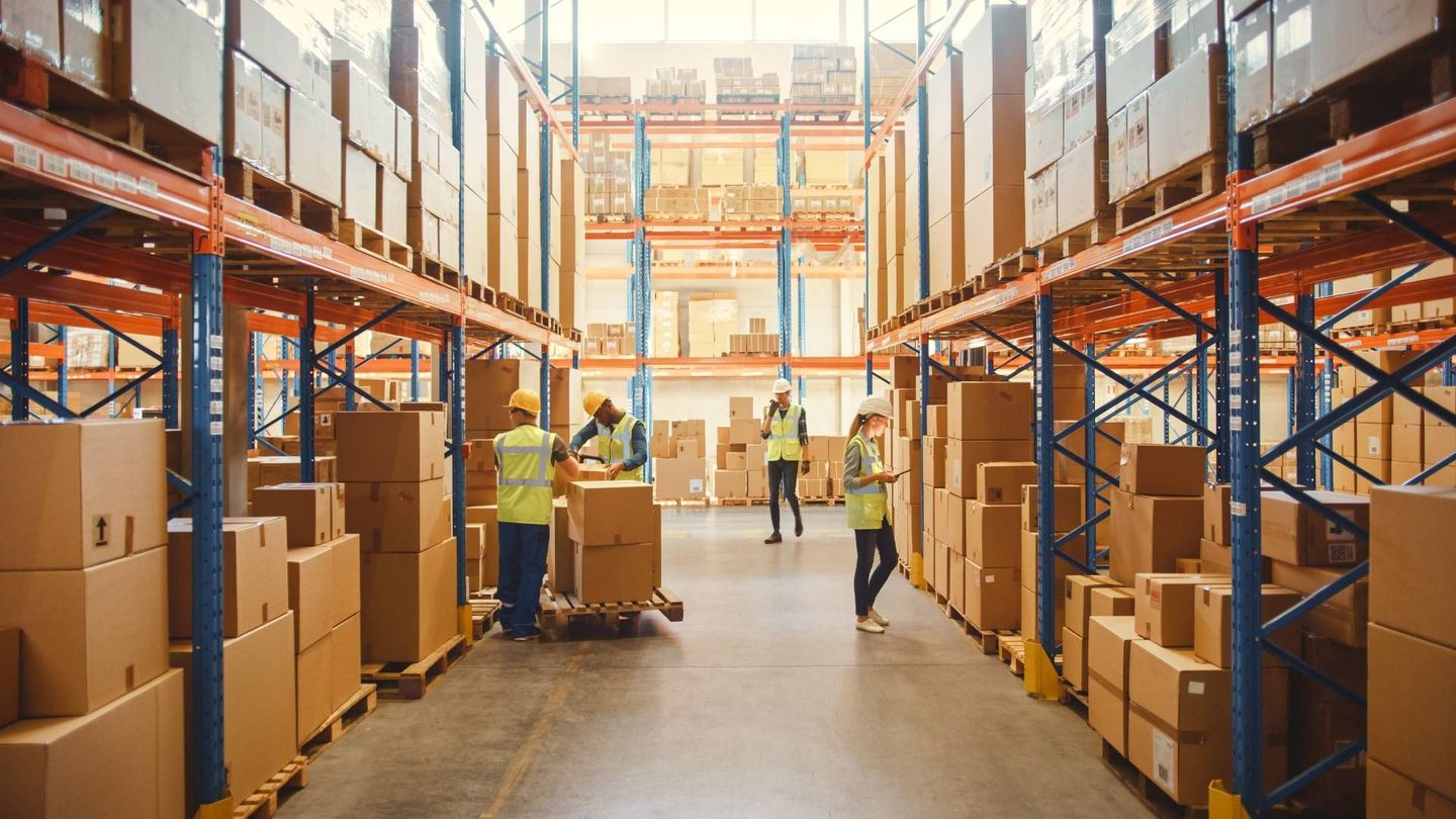 A group of people are working in a large warehouse filled with lots of boxes.