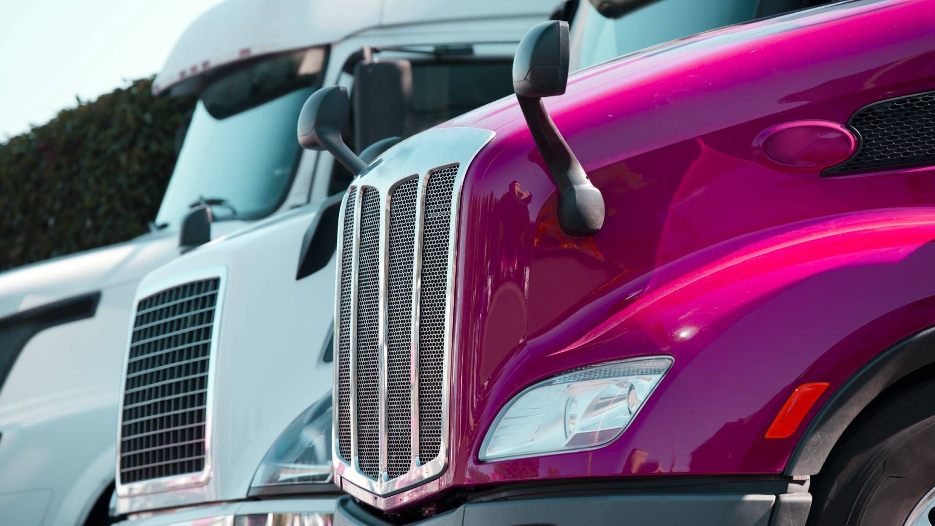 Two semi trucks are parked next to each other in a parking lot.