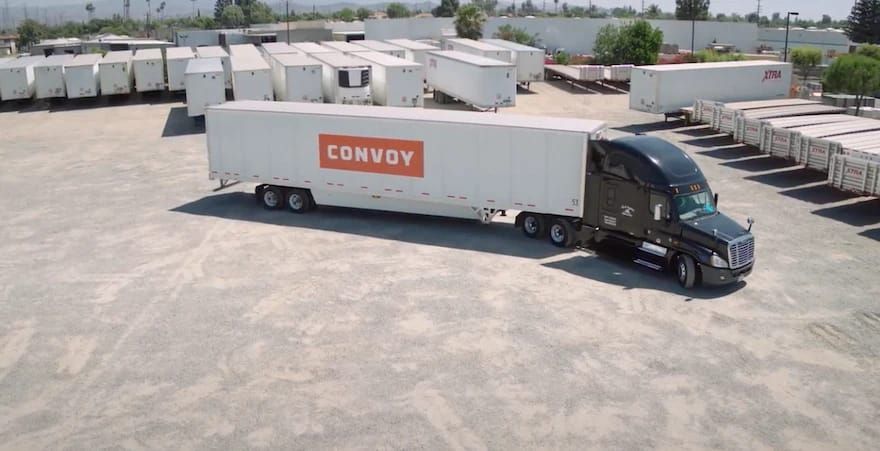 A truck with a trailer that says convoy is parked in a parking lot.