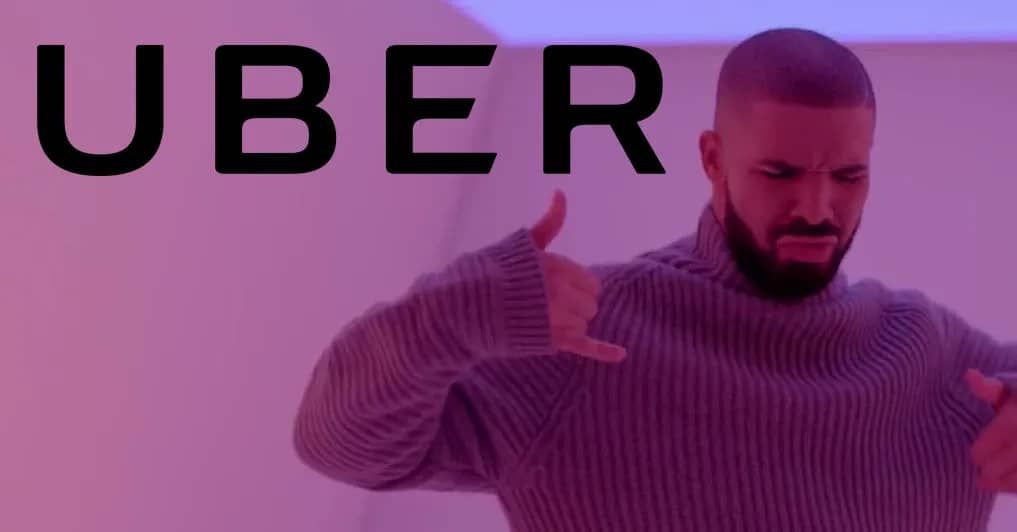 A man in a sweater is giving a thumbs up in front of an uber logo.