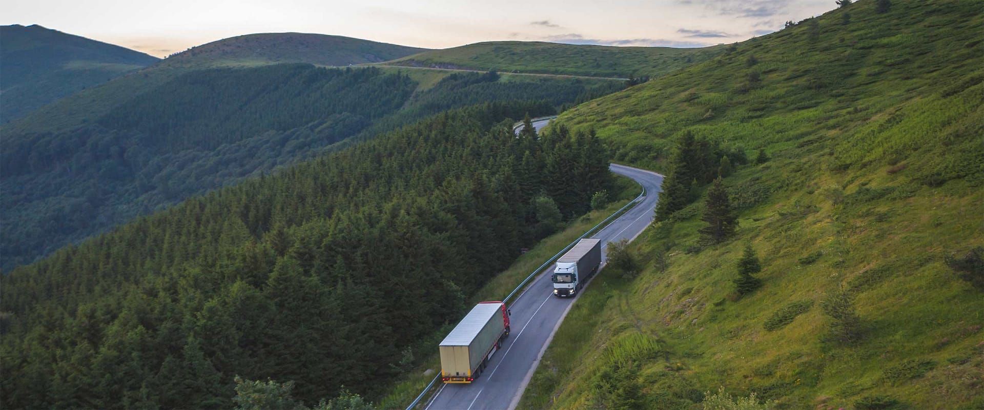 An aerial view of a truck driving down a mountain road.