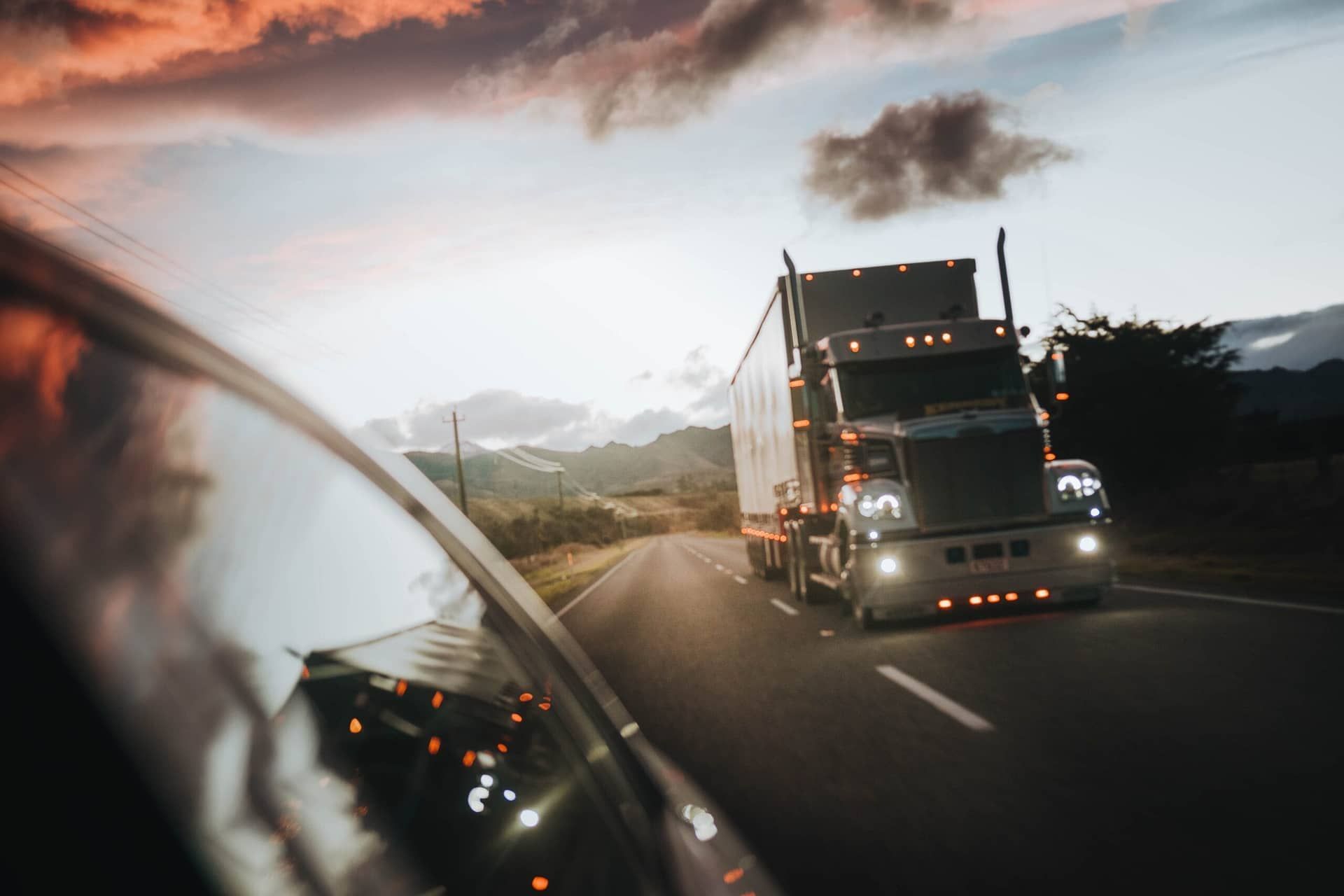 A semi truck is driving down a highway at night.