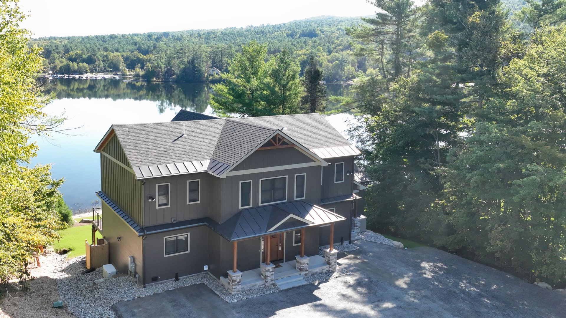 An aerial view of a large house next to a lake surrounded by trees.