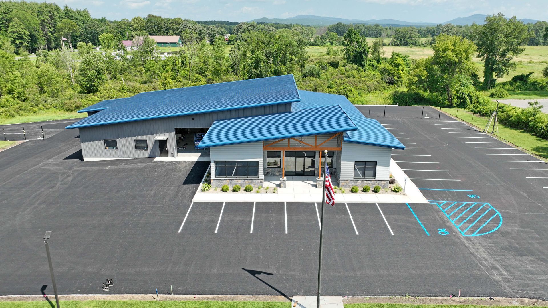An aerial view of a building with a blue roof and a parking lot in front of it.