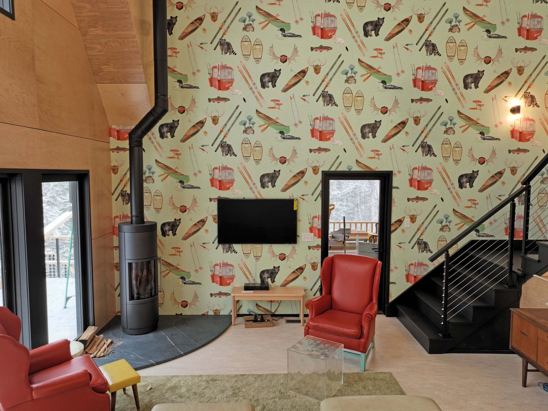 A living room with a staircase and a tv on the wall