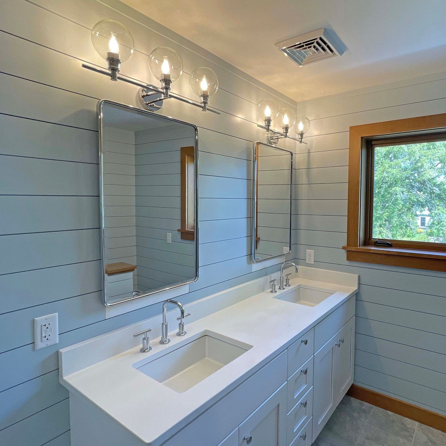 A bathroom with two sinks a mirror and a window
