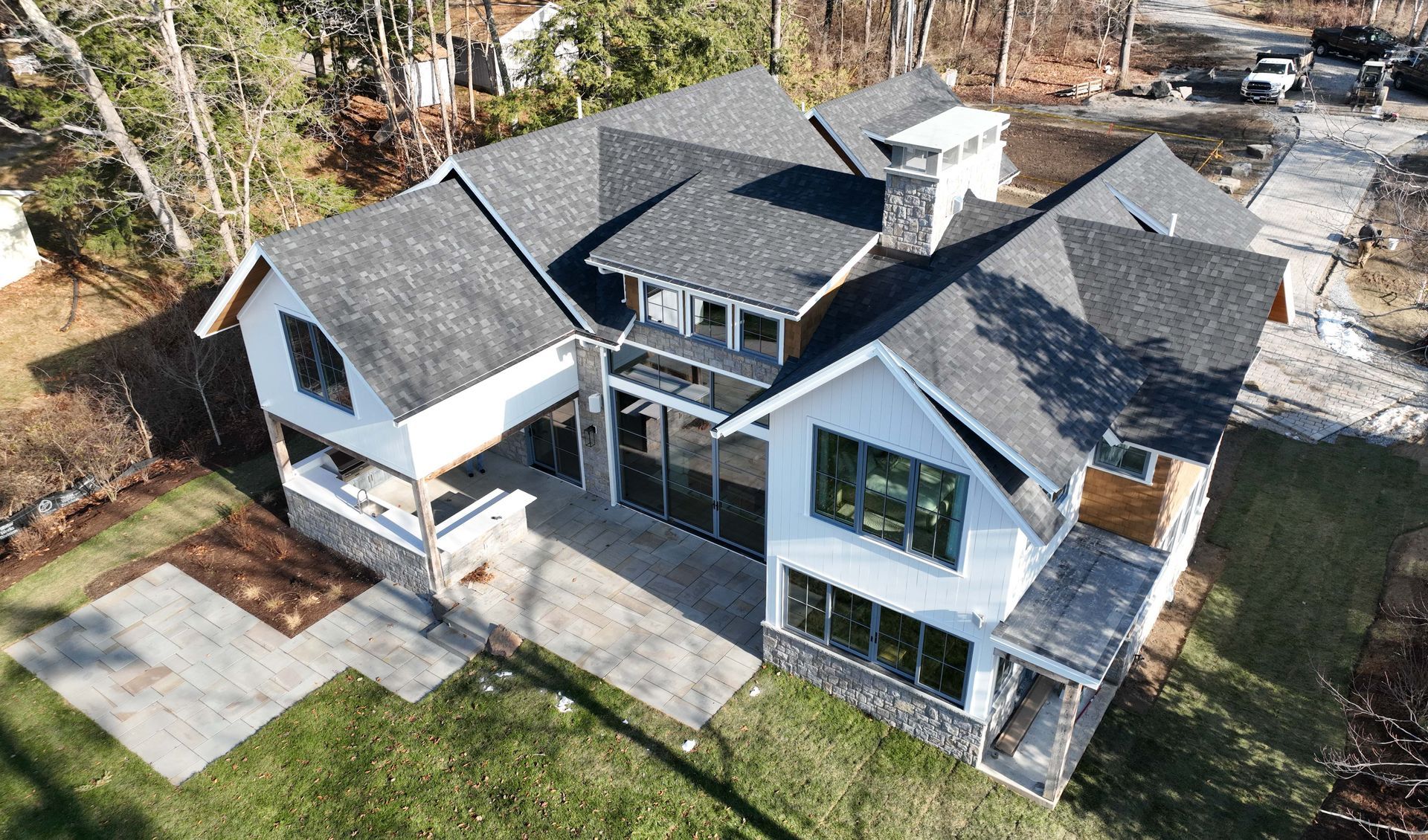 An aerial view of a large white house with a gray roof surrounded by trees.