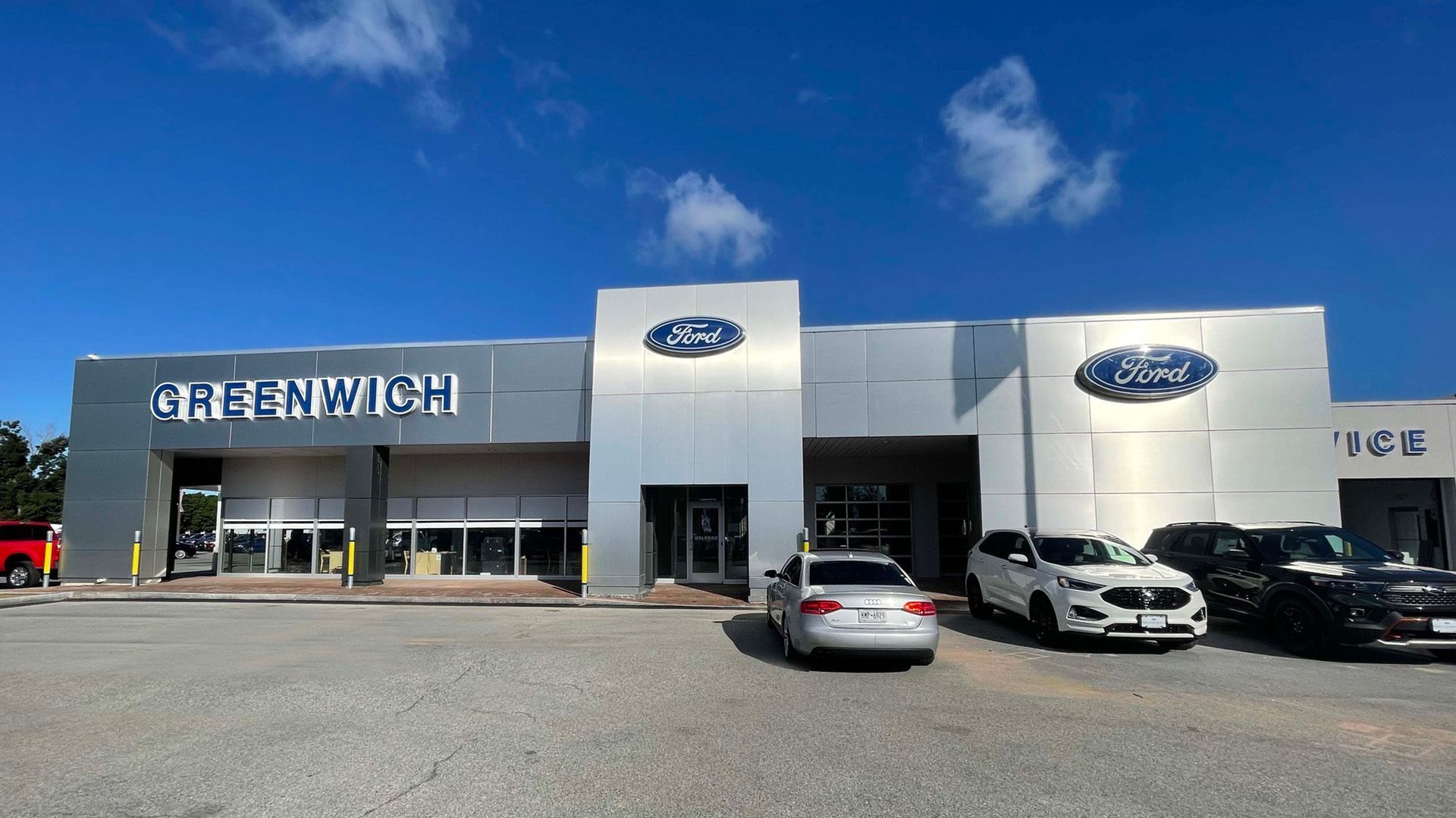 A ford dealership with cars parked in front of it.
