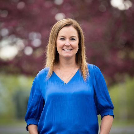 A woman in a blue shirt is smiling for the camera.