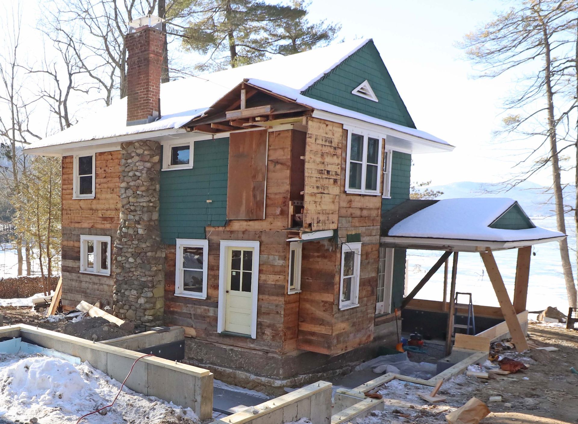 A house with a green roof is being remodeled in the snow