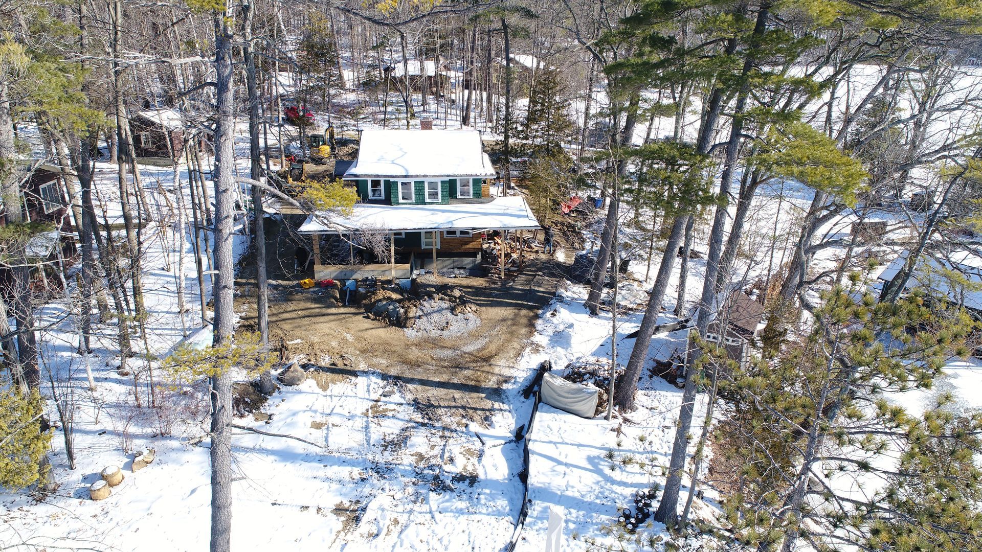 An aerial view of a house in the middle of a snowy forest.