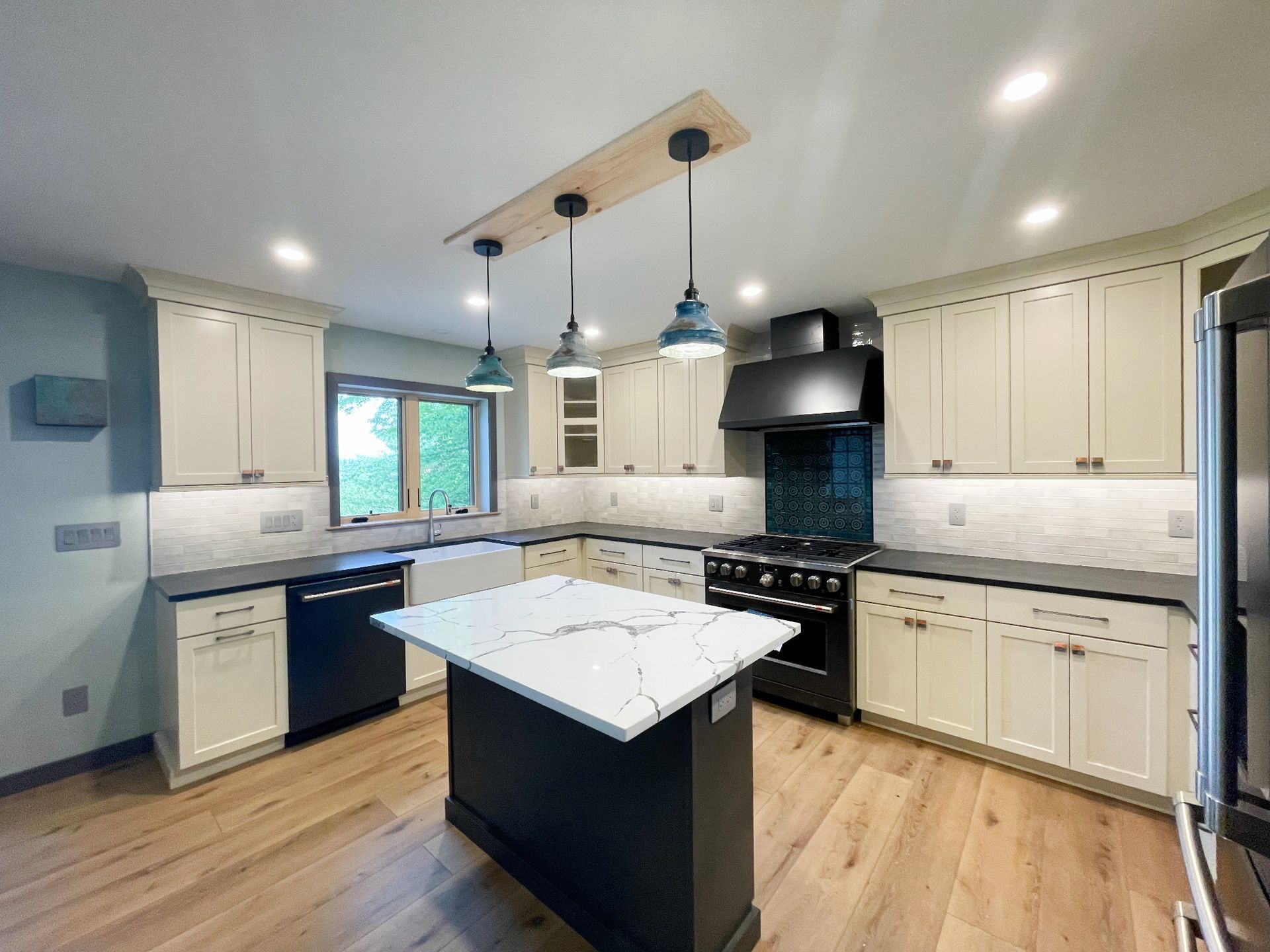 A kitchen with white cabinets , black appliances , and a large island.