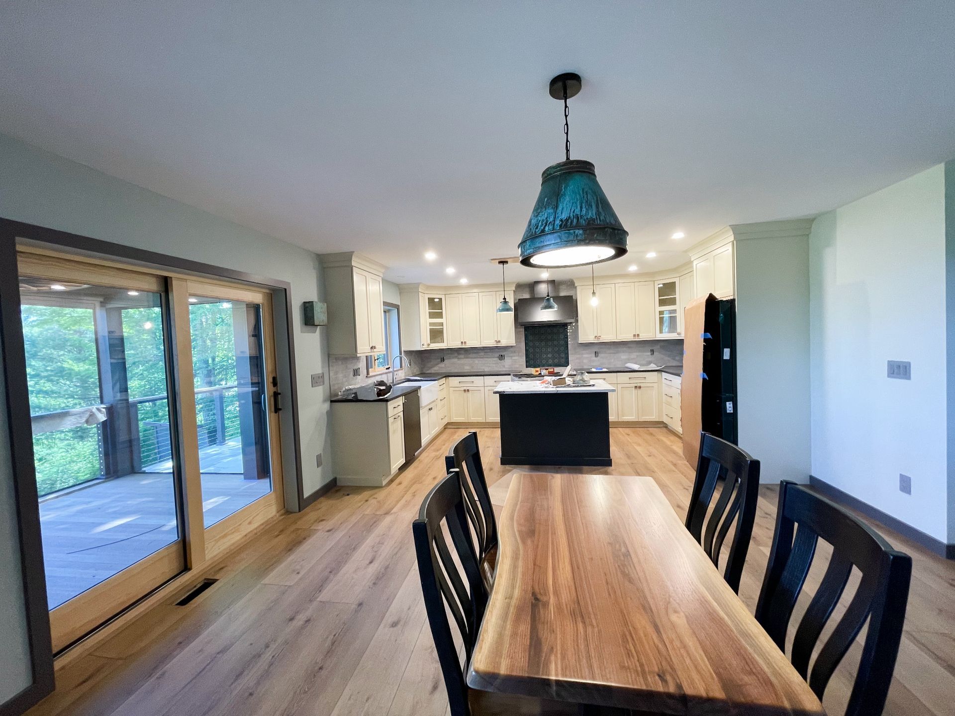 A dining room table and chairs in a kitchen with sliding glass doors.