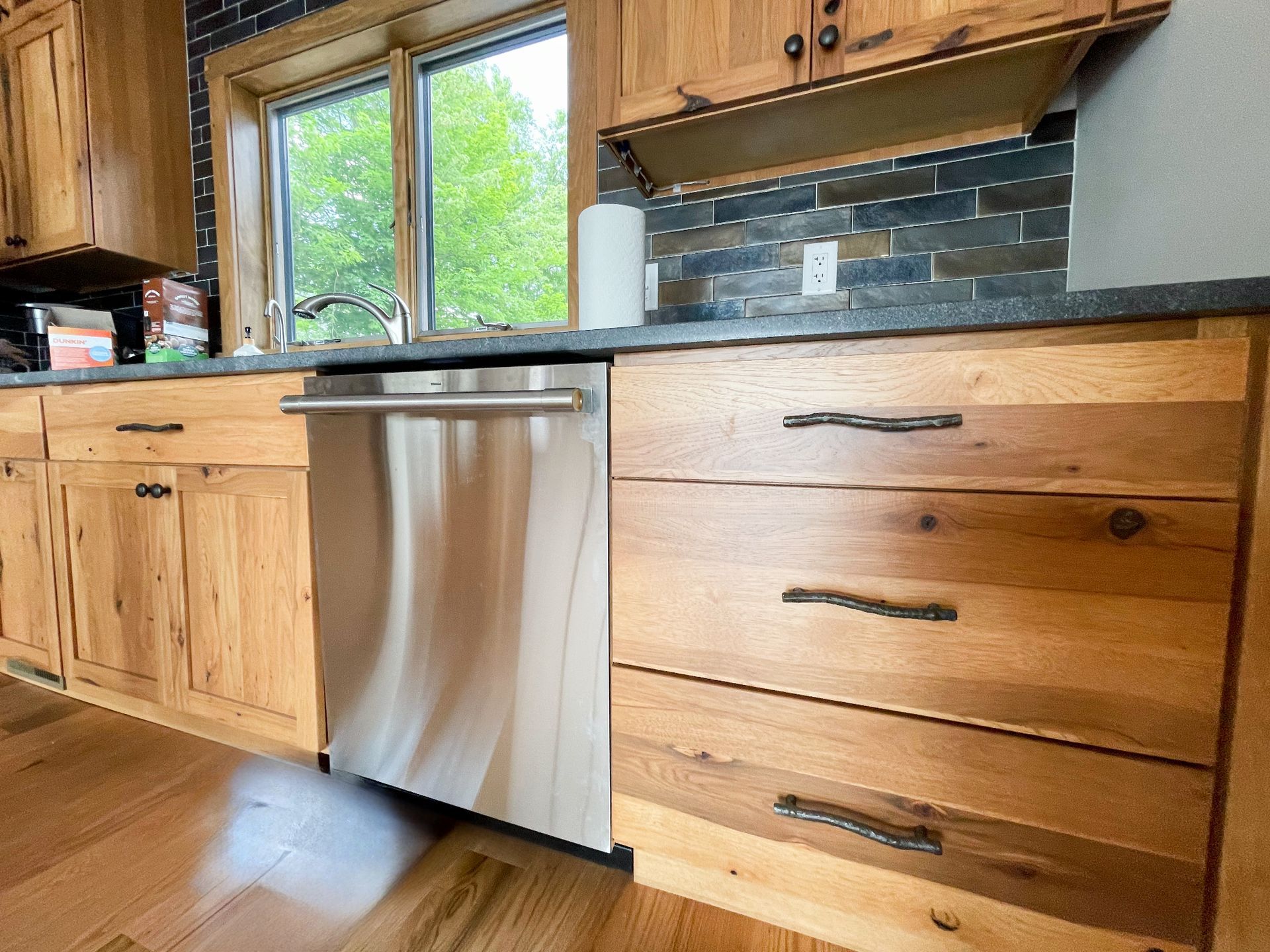 A kitchen with wooden cabinets and a stainless steel dishwasher.