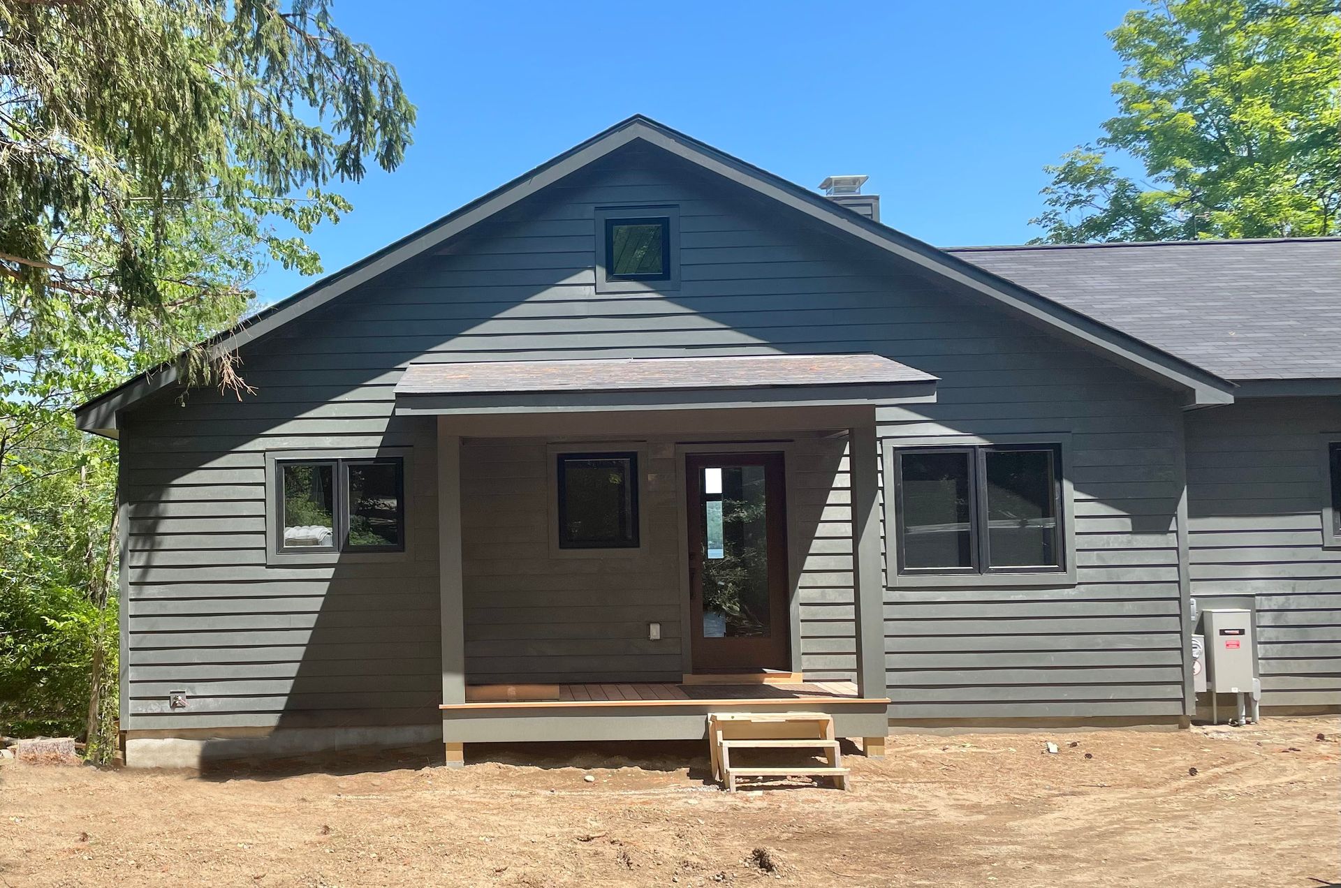 A gray house with a porch and stairs in front of it