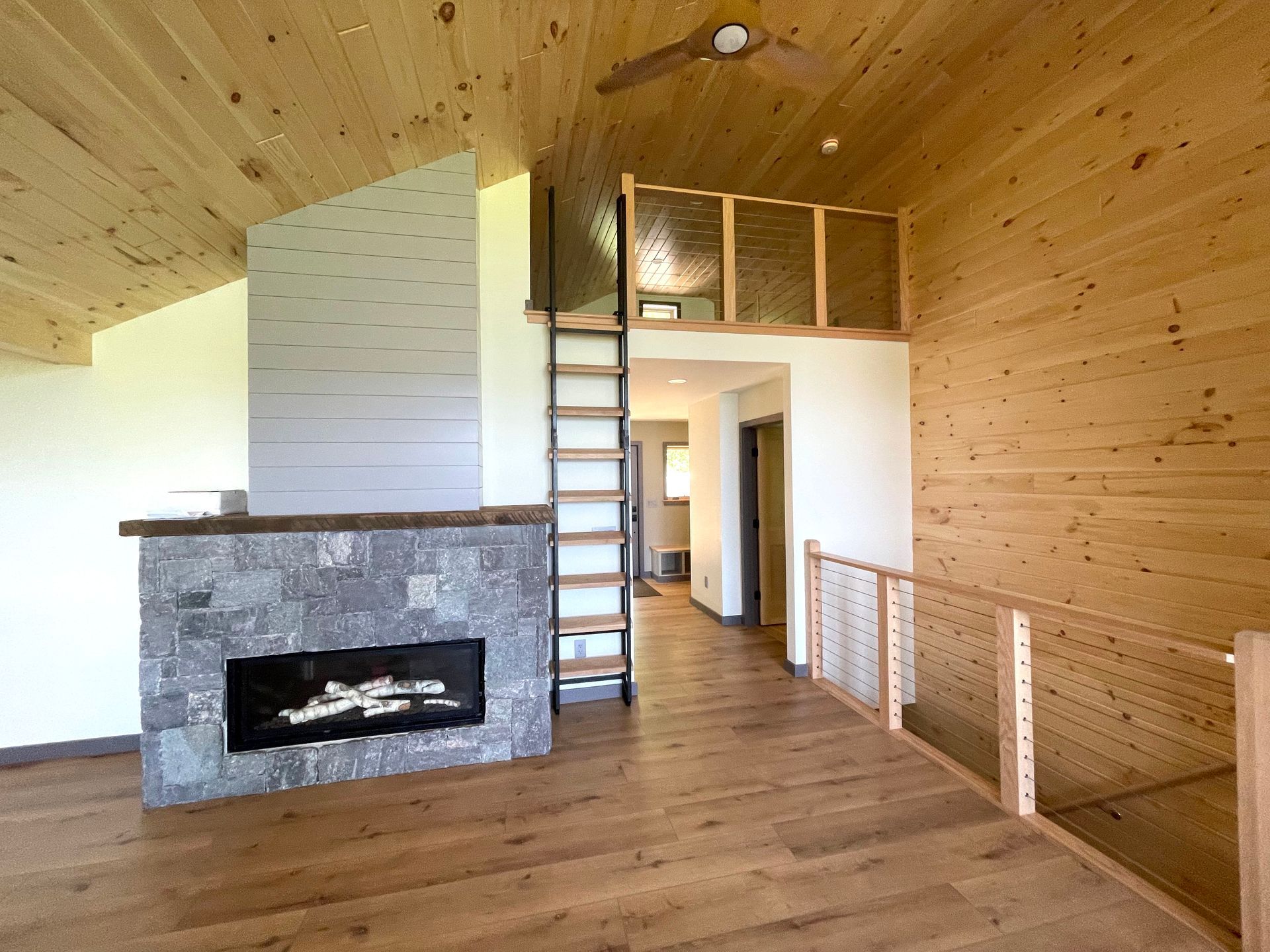 A living room with a fireplace and stairs leading to a loft.